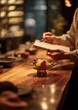 © Nadia - Warm intimate restaurant scene with a glass bowl of colorful fresh fruits and edible flowers on a wooden counter, a person writing in a notebook nearby, cozy bokeh lights in background.