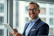 © Creuxnoir - A man in a blue suit and glasses holding a tablet.