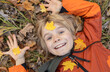 © Anna - Autumn joyful mood. Smiling child lies on the ground against the background of fallen maple leaves. Emotion of happiness. Carefree childhood, rest, walks and enjoyment of warm autumn days.