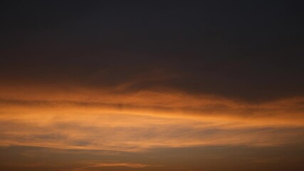 Wall Mural - a rich sunrise sky timelapse with glowing deep orange and amber clouds spreading across a dimming bl