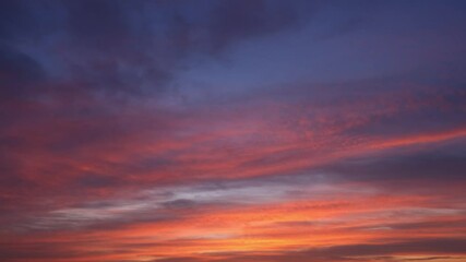Wall Mural - A sunrise timelapse video captures the sky’s breathtaking transformation as warm golden and soft pink hues gradually fade into cool purples and blues. Gentle clouds drift across the horizon. 
