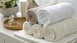 © Jamshadul Alam - A stack of rolled towels in white and beige hues are neatly arranged with decorative items in the background