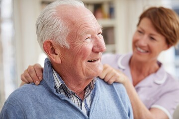 smiling elderly man receiving a caring shoulder massage from a friendly female nurse in a cozy home 
