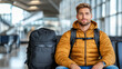 © siraphol - Traveling man with backpack waiting at airport gate, looking relaxed and ready for adventure