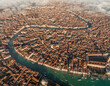 Aerial view of serpentine waterways cutting through a dense city with terracotta rooftops under soft clouds, Venice, Veneto, Italy.