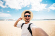 © Davide Angelini - Handsome young man taking selfie picture at beach summer vacation - Smiling guy having fun walking outside - Summertime holidays and technology concept
