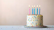 © Mangtraa - A small birthday cake with five lit candles on a white surface against a pale pink background.