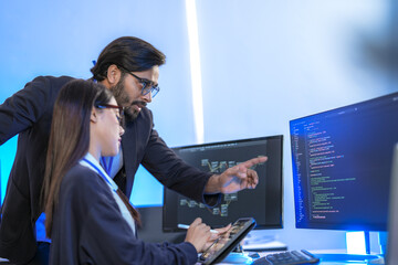 asian female ai programmer and indian male data analyst reviewing code on a monitor. diverse tech pr