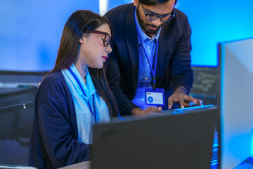 Asian female AI programmer and Indian male data analyst reviewing code on a monitor. Diverse tech professionals collaborating on an artificial intelligence project in a modern office.