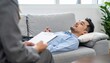 © photostockatinat - Therapy session scene, showing a patient lying on a couch and counselor talking. The image evokes feelings of trust, and care