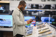 © Serhii - Customer comparing smartphones in electronics store