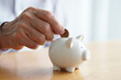 © Nicole - Elderly hand putting coin into white safe