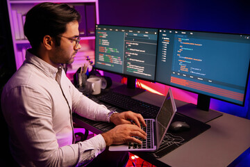 smart it developer working on laptop to type searching in software coding system at neon light offic