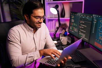 Smart IT developer working on laptop to type searching in software coding system at neon light office room, creating application program update latest version online website database online. Surmise.