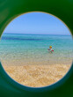 © Elena - View of Child Playing in the Sea Through Beach Ring