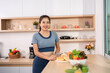 © wichayada - ESG and Healthy Living. Cheerful woman posing with fresh ingredients in her kitchen.