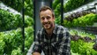 © CStock - A smiling man in a greenhouse surrounded by vibrant, fresh greenery, showcasing sustainable urban farming.