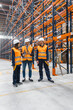 © Koldo_Studio - Warehouse workers wearing safety vests and hardhats are discussing logistics and inventory management in a large distribution center