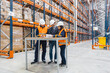 © Koldo_Studio - Warehouse workers and manager wearing safety vests and hardhats are checking inventory and logistics using documents and barcode scanners in a large distribution center