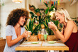 © djile - Two women are enjoying a coffee break together in a modern cafe, laughing and chatting