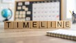 © N7 - Wooden blocks arranged as 'TIMELINE' with blurred project planning board in background