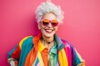 © nsit0108 - Portrait of a cheerful mature woman with colorful clothes and sunglasses posing against a vibrant pink background