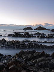 Wall Mural - layers of rock on the coastline at dawn.