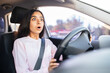 © Anastasiya - Shocked Indian woman driver looking ahead in fear, gripping steering wheel tightly. Illustrates sudden danger, panic or unexpected road situation inside car, closeup