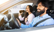 © Anastasiya - Indian woman singing with smartphone while her boyfriend driving car. Cheerful spouses expressing fun, discovery, and tech savvy moment during joyful car ride, closeup