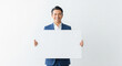 © PixelDust_ - Smiling Asian Business Man Holding Blank Sign Board Against White Background