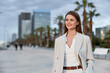 © SHOTPRIME STUDIO - Confident businesswoman smiling outdoors in a modern urban environment, dressed in a stylish light suit and enjoying a sunny day.