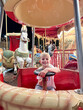 © Elena - Child Enjoying Carousel Ride at Night Carnival