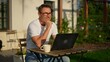 © nyul - Happy businessman working remotely in garden. Mature man using laptop computer outdoor in morning with coffee. Male entrepreneur freelancer tele working online in home office. Digital business life.