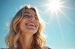 © Vadym - Radiant young woman with blond hair smiles brightly against clear blue sky. Bright sunshine illuminates face, emphasizing youthful beauty, joyful expression. Enjoys warm summer day outdoors, exuding
