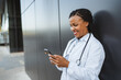 © Miljan Živković - african american woman doctor use cellphone in front black background