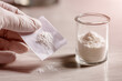 © tai - Close-up of a person wearing gloves handling a powder sample