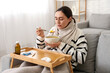 © Pixel-Shot - Sick young woman eating soup on sofa at home
