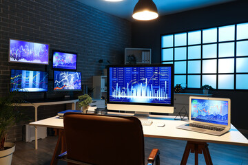 Wall Mural - computer and laptop with stock data on trader's desk in dark office at night