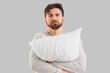 © Pixel-Shot - Upset young man with soft pillow on light background