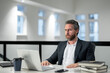 © Volodymyr - Handsome 40s business man working with laptop in office. Gray hair mature business man director using laptop. Millennial manager at office workplace. Ceo office workers business people at office.