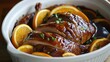 © rehan - Sliced roasted duck with orange slices in a savory sauce.