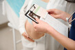 © Василь Івасюк - Cropped view of female doctor showing prescription or notes on clipboard to pregnant woman during prenatal care visit in clinic. Pregnant woman receiving prenatal care from doctor. Fetal care