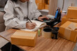 © kamiphotos - she in an entrepreneur, she sells product online, she own a small business that sell product online, sme, a lot of parcel stack in the room, working in her shopping online storage