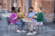 © sofiko14 - A diverse group of friends enjoys pizza and drinks together at an outdoor cafe.
