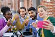 © sofiko14 - Friends enjoy sushi together, taking a selfie outdoors. They are smiling and having fun.