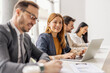 © Dusan Petkovic - Selective focus on smiling businesswoman typing on a laptop and sitting with her leadership team at conference room.