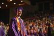 © Martinesku - A cheerful graduate in a purple gown smiling proudly amidst a joyful graduation ceremony celebration, with background audience clapping and showing support.