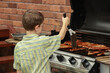 © Austockphoto - Young boy cooking sausages on the barbecue