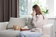 © New Africa - Woman suffering from allergy with her cat on sofa at home