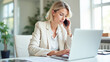 © Radorog. - A business woman is talking on the phone while sitting in front of her laptop in the office